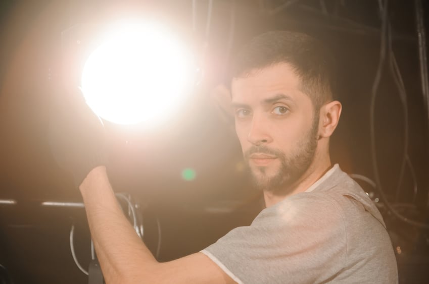 Film electrician adjusting light on set