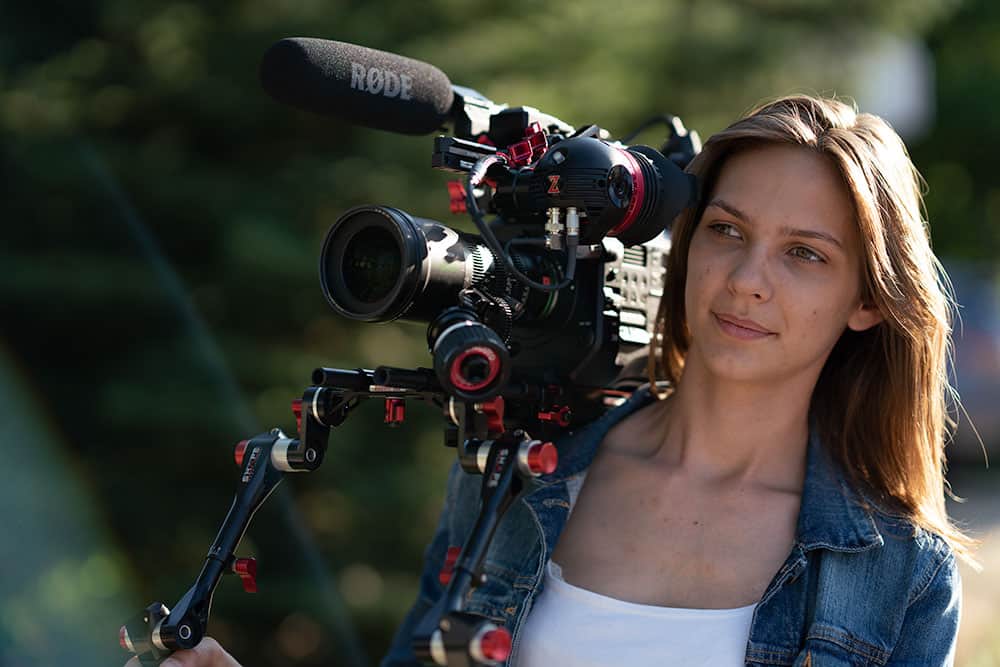 Female filmmaker with large camera outdoors