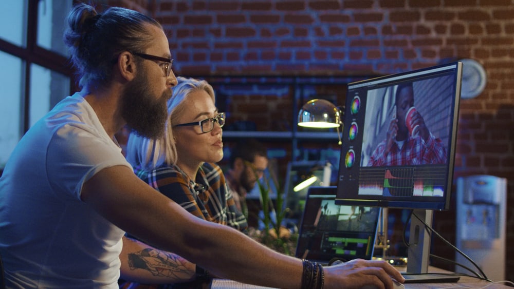 Male and female filmmakers editing YouTube videos on a computer