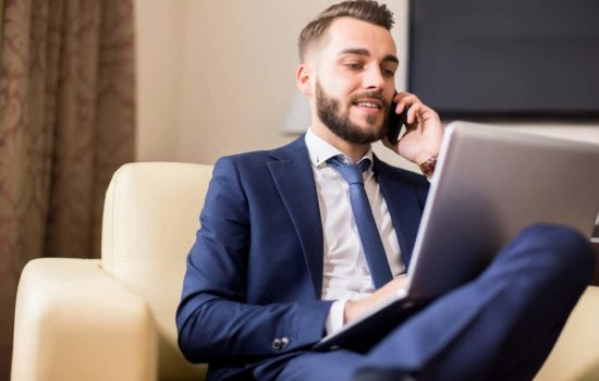 Manager talking on his cell phone while looking at his laptop