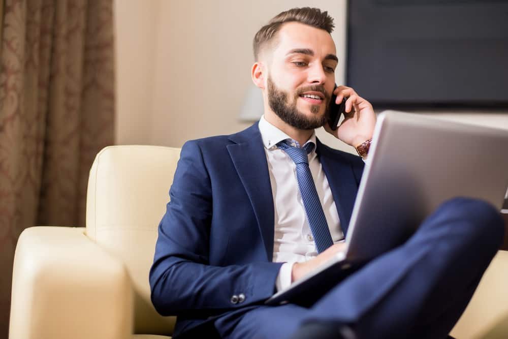 Manager talking on his cell phone while looking at his laptop