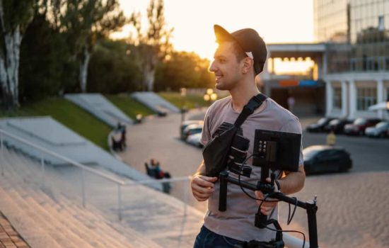Young male filmmaker shooting short films outdoors with his camera gear