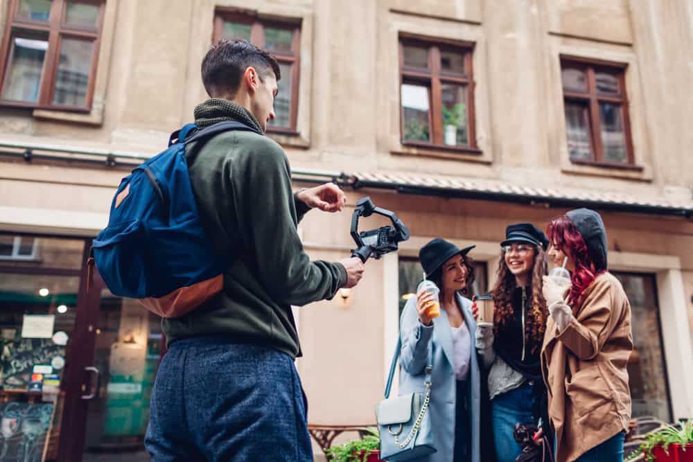 Man filming three women hanging out with handheld camera gear