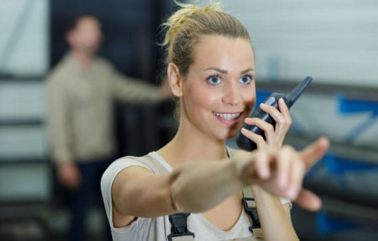 Female Key PA talking into walkie talkie on set