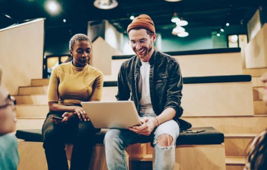 Male and female screenwriting duo looking at a laptop