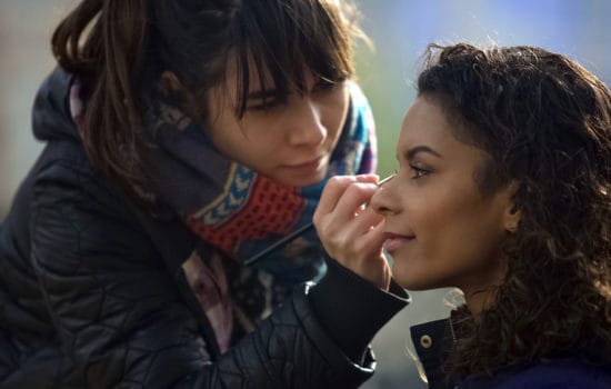 Assistant makeup artist fixing makeup for actress on location