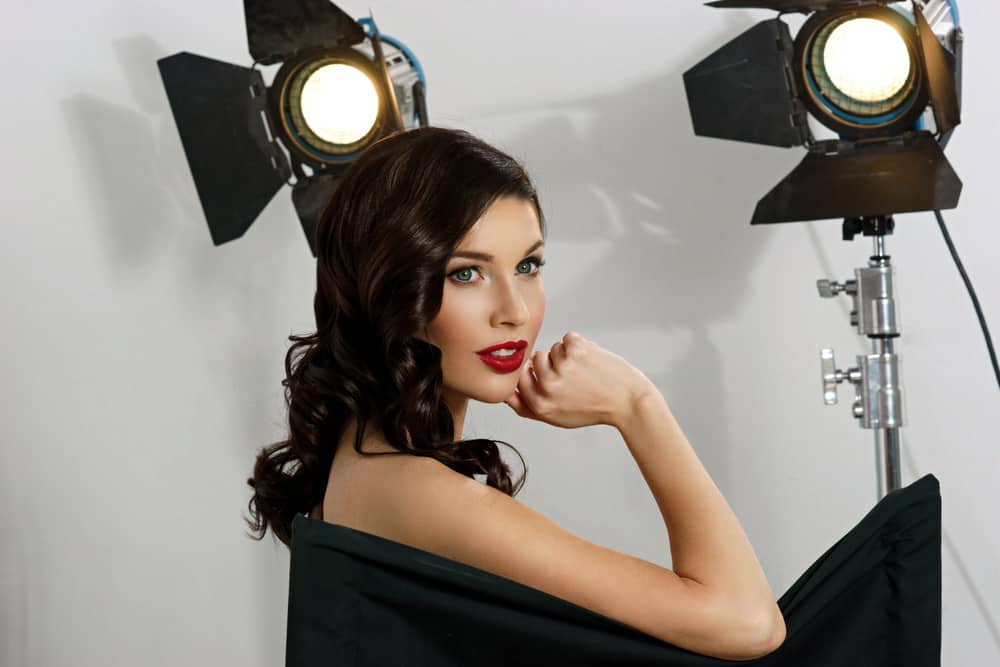 Actress sitting in chair with lights on set