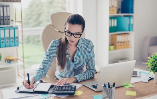 Assistant production accountant crunching numbers at her desk