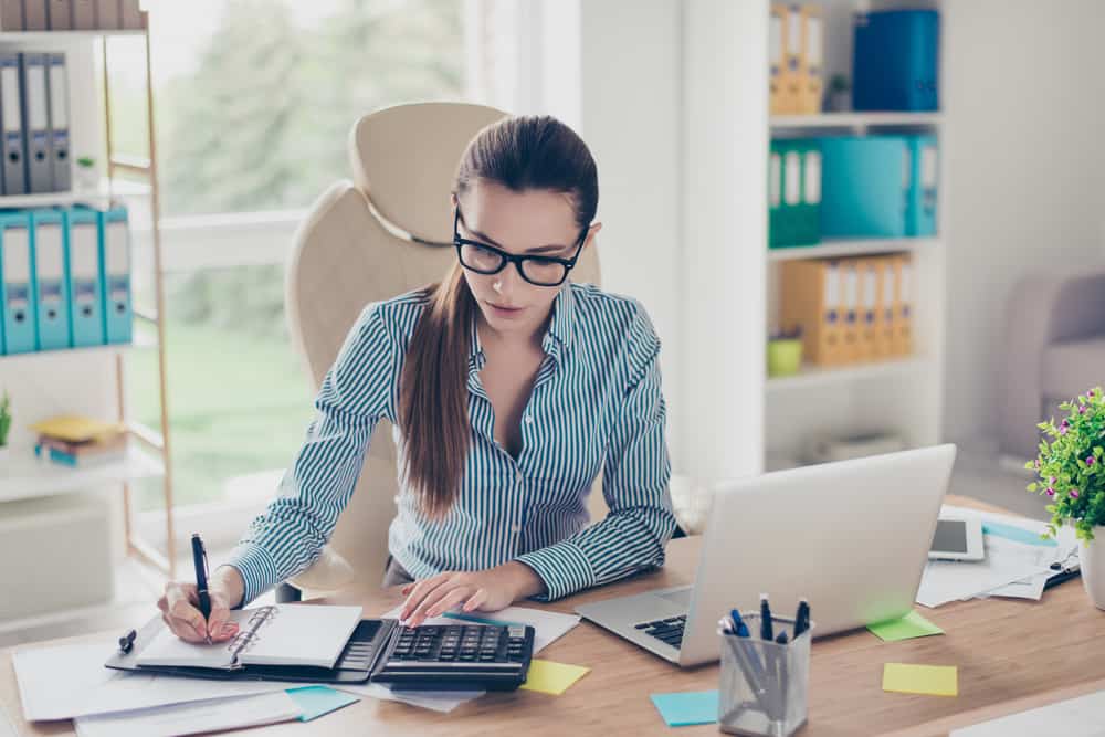 Assistant production accountant crunching numbers at her desk