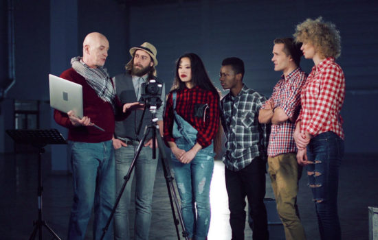 Top film school students and their professor looking at a camera on a sound stage