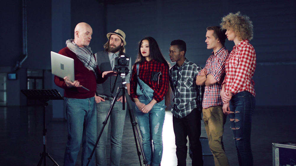 Top film school students and their professor looking at a camera on a sound stage