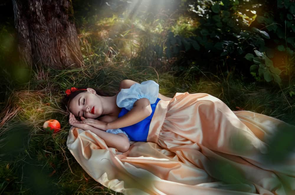 Actress dressed as Snow White sleeping on grass