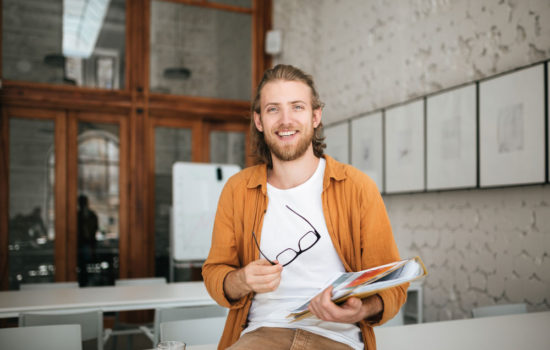 Hip young male film professor in empty classroom