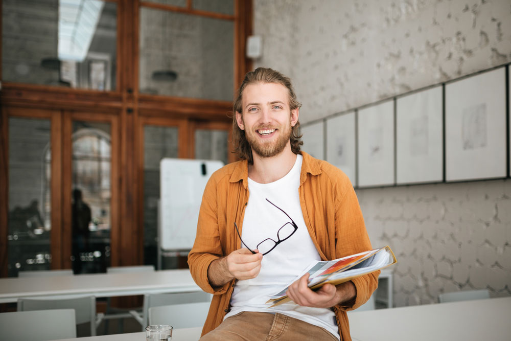 Hip young male film professor in empty classroom